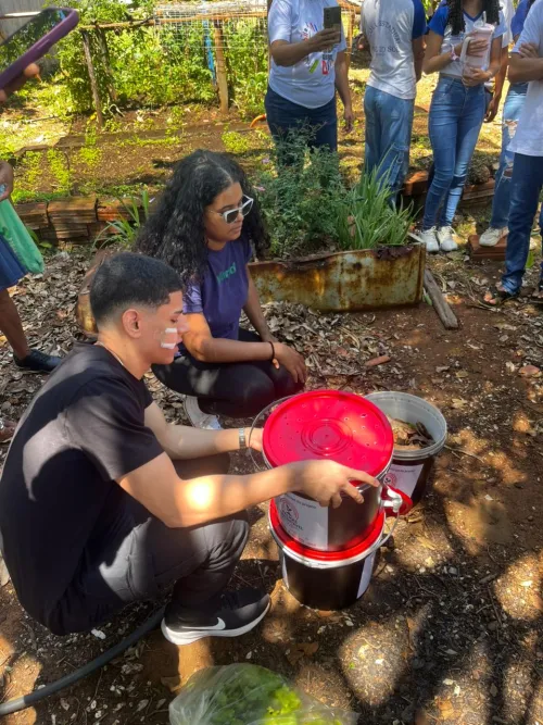 Alunos reunidos ao redor de uma &aacute;rvore para a dinamica de composteiras